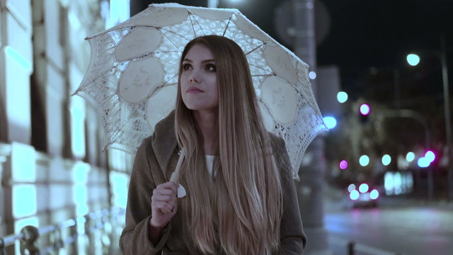 blonde woman holding a bunch of roses in a rainy day walking with the umbrella e