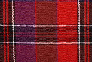 Scottish tartan pattern. Red and purple plaid print as background. Colored lines and square pattern. Scottish checked fabric.