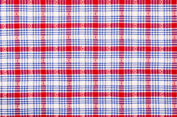 Close up on checkered tablecloth fabric. Red and blue with hearts tartan square pattern as background.