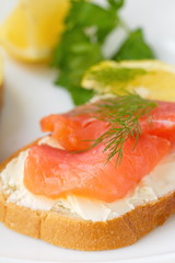 Sandwich with smoked salmon, cream cheese and lemon on plate