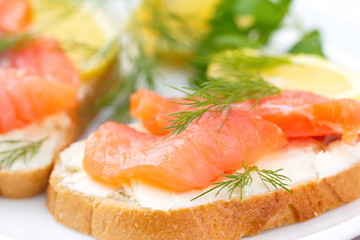 Sandwich with smoked salmon, cream cheese and lemon on plate