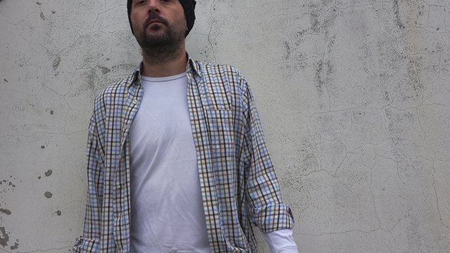 Nervous rude man showing middle finger as an insulting gesture, adult male punk on the street.