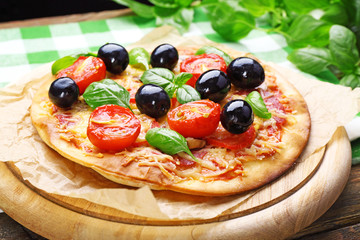 Tasty pizza with vegetables and basil on table close up