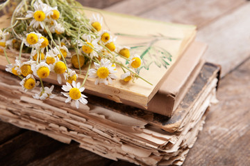 Old books with dry flowers on table close up