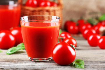 Glasses of tomato juice with vegetables on wooden table close up