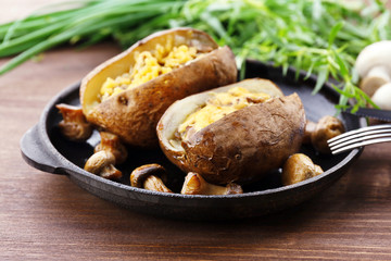 Baked potatoes with cheese and mushrooms on table close up