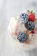 Delicious ice cream with fresh frozen berries, on color wooden background
