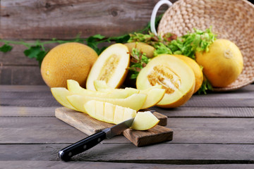 Ripe melons with green leaves on table close up