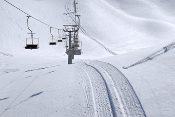 Wyciąg krzesełkowy i ślady ratraka (snowgroomer) w śniegu na przełęczy Presena, Passo Tonale - obrazy, fototapety, plakaty