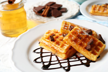 Sweet homemade waffles with chocolate sauce on plate, on light background