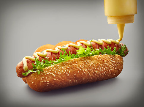 Hot dog with pouring mayonnaise
