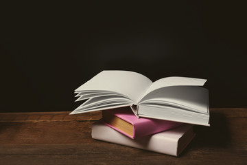 Pile of books on wooden table against black background