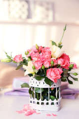 Beautiful rose in vase on table in room on bright background