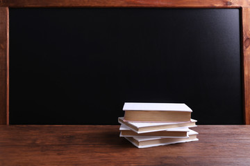 Books on the table on blackboard background