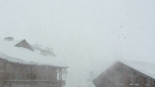 Snow blowing by a chalet in the French Alps. 