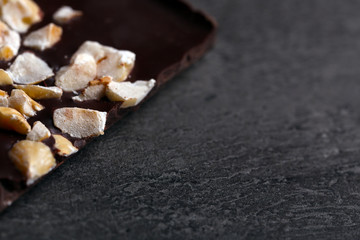 Black chocolate pieces and nuts on dark gray background