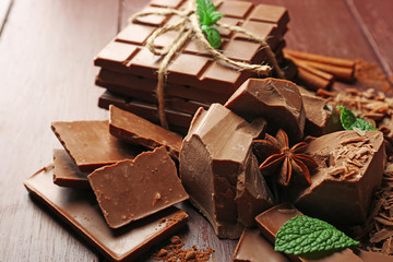 Variety of chocolate pieces, coffee grains and cocoa powder on wooden background