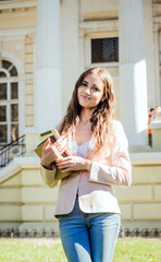 young caucasian female student with books and tablet on campus, student study in campus area