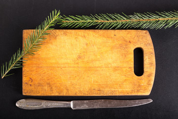 Table-knife, cutting board and green fresh branch of Cristmas tr