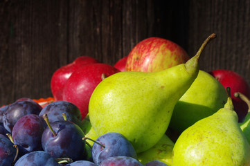Plums, pear and apple on a wooden background. Fresh autumn crop of fruit.