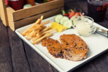 Pork steak set placed on a wooden table restaurant.