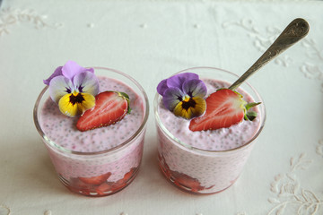 Homemade pink Chia pudding with strawberry and edible flowers