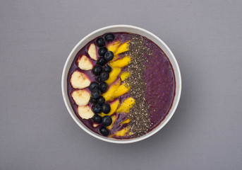 acai smoothie bowl topped with chia seeds, mango slices, blueberries and bananas