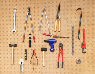 An array of tools hanging up on a peg board wall.