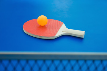 pingpong racket and ball and net on a blue pingpong table