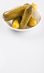 Dill pickles in a white bowl over white background