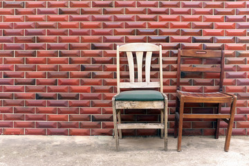 two old chairs outside on the sidewalk against red brick wall