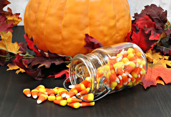 Candy corn in a mason jar spilling onto a table decorated for au
