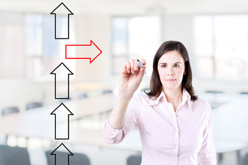 Businesswoman drawing arrows in different directions. Office background.