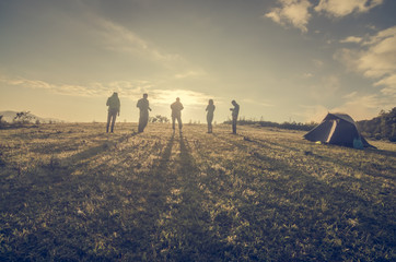 Group Of People relaxing on field with sunrise