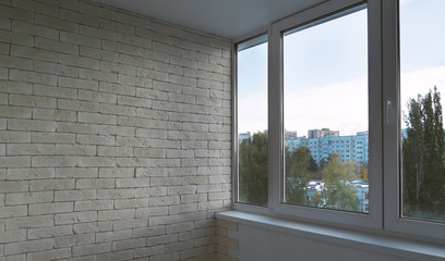 Fototapeta premium Balcony window beside white brick wall provides a bright interior view of urban apartment buildings, ideal for real estate design, home renovation, and architectural marketing