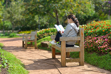 Fototapeta premium Young woman sitting in the park reading a book
