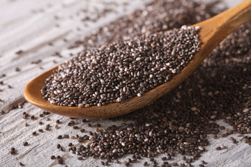 Chia seeds in a wooden spoon on the table close-up. horizontal
