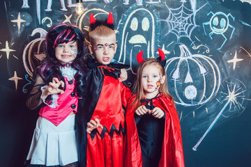 Fototapeta premium Girls, dressed up in Halloween costumes, show emotions of witches . Halloween party with group children.