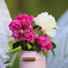 Pink peonies in vase on wooden table on green background. Festival decoration