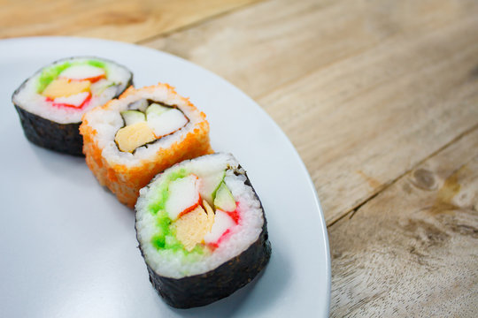 Sushi maki on a plate over wooden table