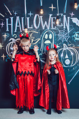 Girl and boy, dressed up in Halloween costumes, show emotions of witches . Halloween party with group children.