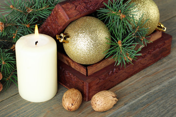 Christmas toys in wooden box near to the candle on wooden brown background, Christmas composition.