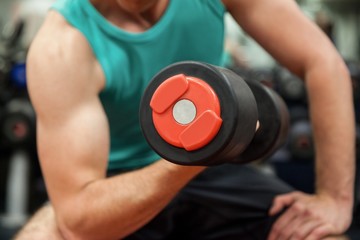 Man lifting dumbbell weight while sitting