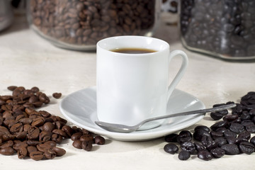 Cup of coffee beside natural roasted and torrefacto coffee beans