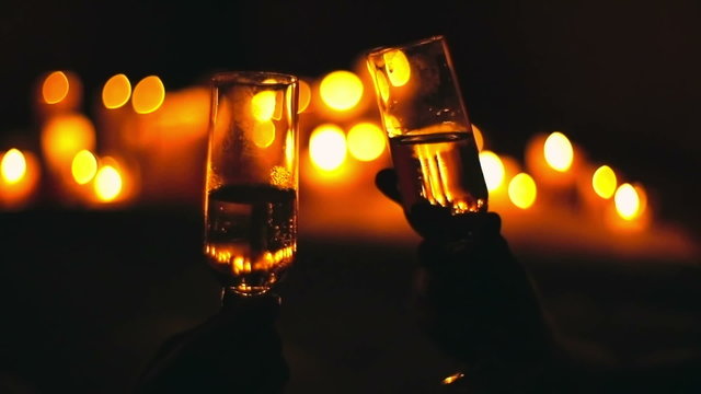 Backlit shot of couple toasting champagne flutes and kissing in candlelight 