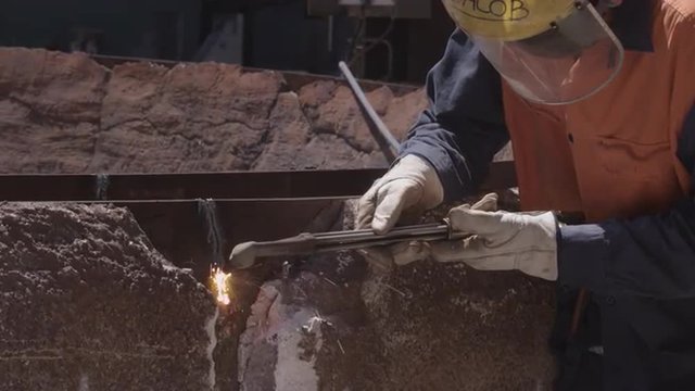 Industrial worker using welding equipment to cut steel. 