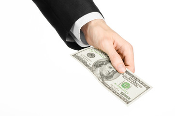 Money and business topic: hand in a black suit holding a banknote of 100 dollars on white isolated background in studio