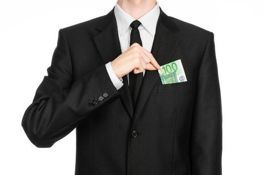 Money and business theme: a man in a black suit holding a banknote 100 euro isolated on a white background in studio