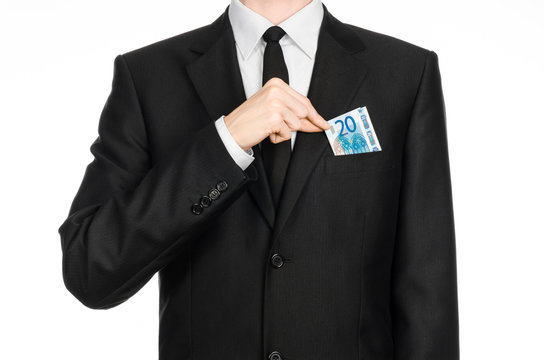 Money and business theme: a man in a black suit holding a bill of 20 euros and shows a hand gesture on an isolated white background in studio
