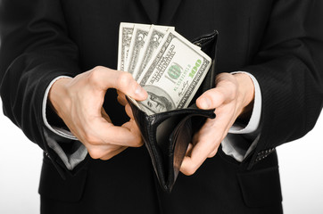 Money and business theme: a man in a black suit holding a purse with paper money dollars isolated on white background in studio